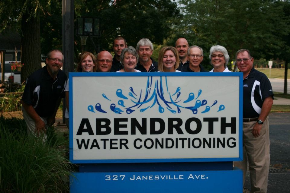 Abendroth Water staff posing for photo around sign
